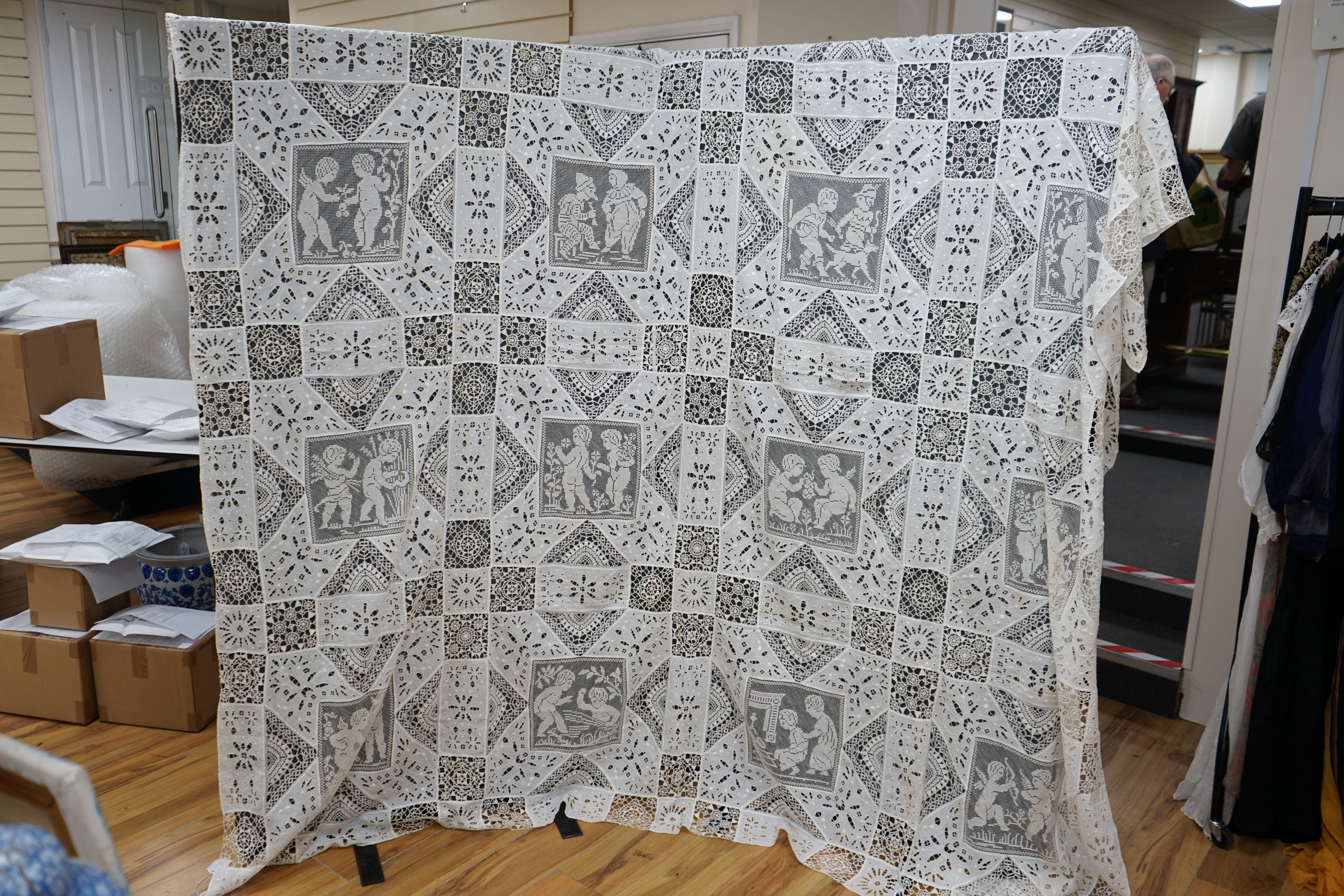 An early 20th century Italian ornate bedcover, worked with square fillet lace insertions of putti, white multi patterned cut work squares on fine linen and similar multi patterned needle lace squares, creating a unique b